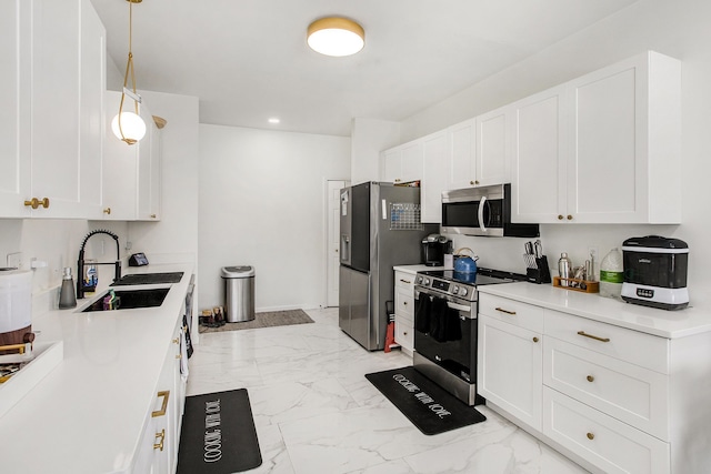 kitchen featuring appliances with stainless steel finishes, sink, pendant lighting, and white cabinets