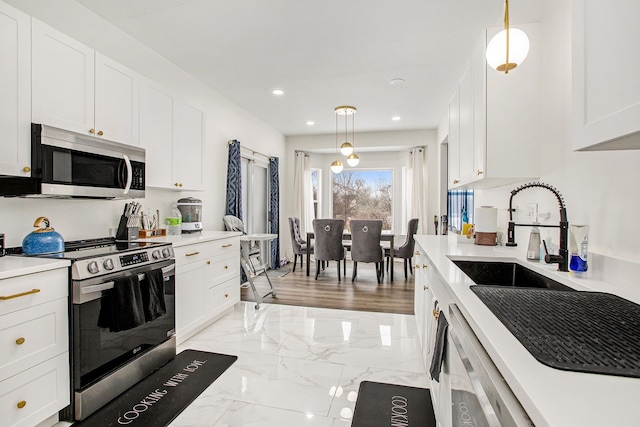 kitchen featuring white cabinetry, appliances with stainless steel finishes, sink, and pendant lighting