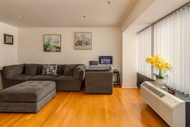 living area with recessed lighting, baseboards, a wall unit AC, and light wood finished floors