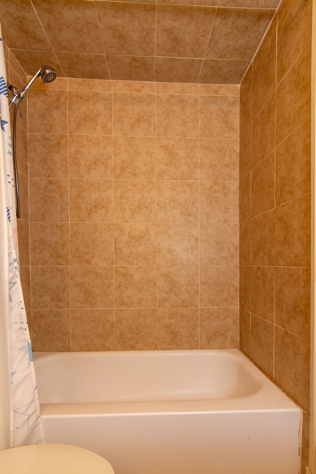 bathroom featuring shower / tub combo and toilet