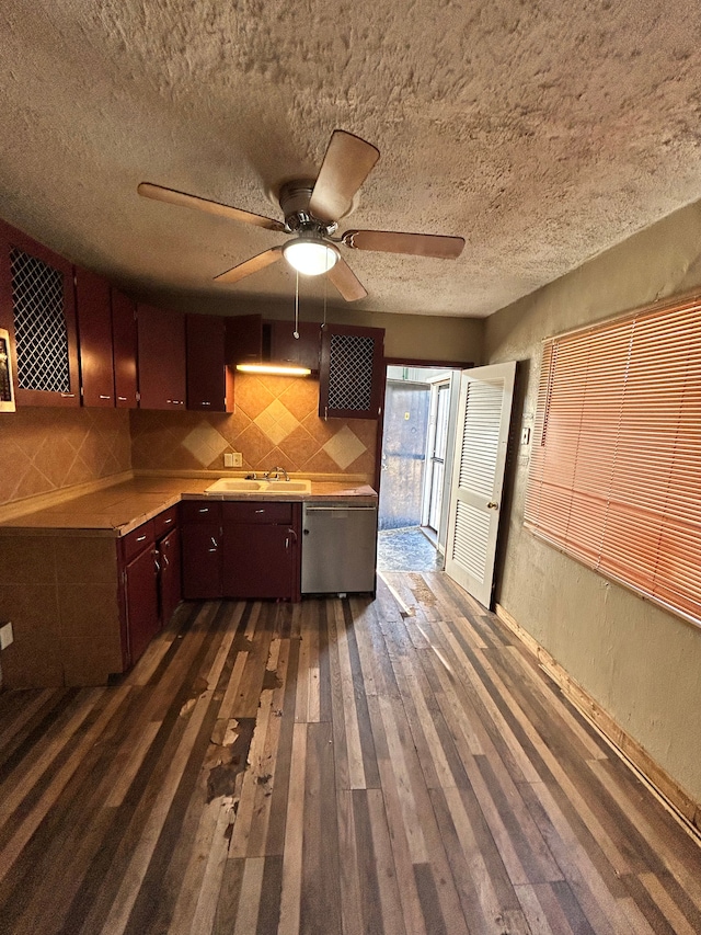 kitchen with sink, dark wood-type flooring, ceiling fan, tasteful backsplash, and stainless steel dishwasher