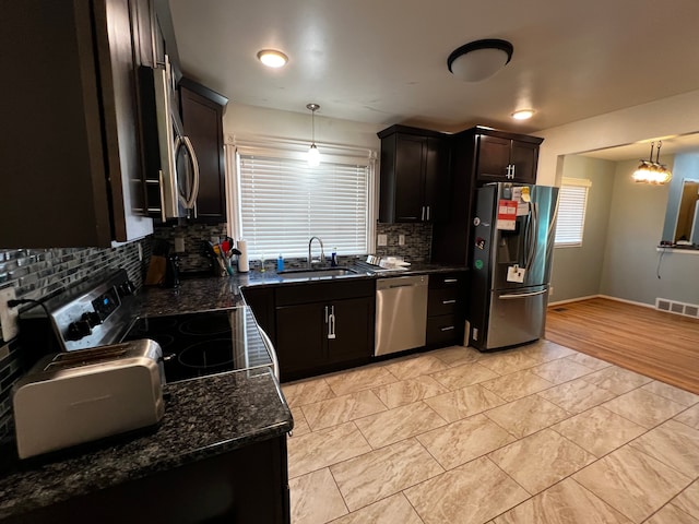 kitchen with pendant lighting, sink, dark stone counters, and appliances with stainless steel finishes