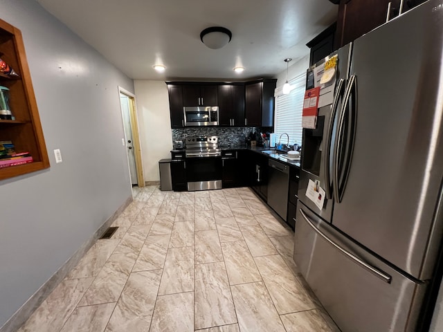 kitchen featuring hanging light fixtures, appliances with stainless steel finishes, sink, and decorative backsplash