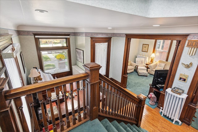 stairway featuring hardwood / wood-style floors and radiator heating unit