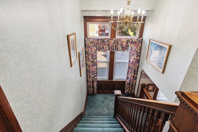 staircase featuring carpet floors and a chandelier