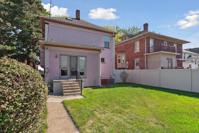 back of house featuring central AC and a lawn