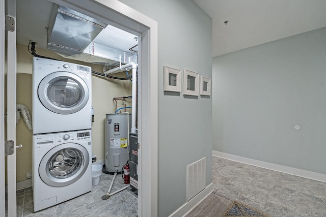 washroom featuring stacked washer / drying machine and water heater