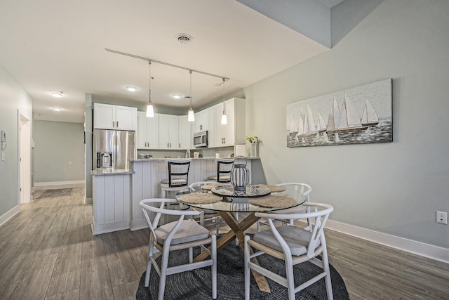 dining area featuring dark wood-type flooring and track lighting