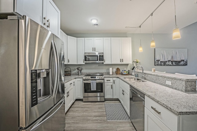 kitchen with decorative light fixtures, stainless steel appliances, kitchen peninsula, and white cabinets