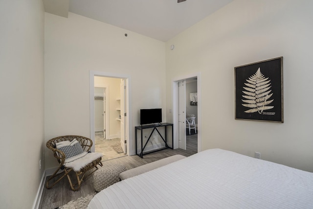 bedroom with a high ceiling, ensuite bathroom, and light hardwood / wood-style flooring