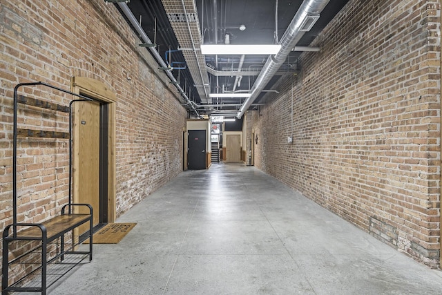 corridor featuring concrete flooring, a high ceiling, and brick wall