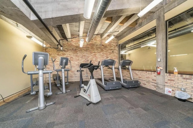 workout room featuring brick wall