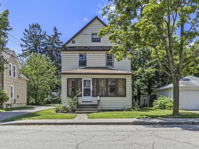 view of front of house featuring a garage, an outdoor structure, and a front lawn