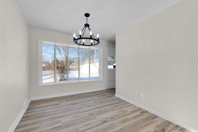 unfurnished dining area featuring a notable chandelier and light hardwood / wood-style flooring