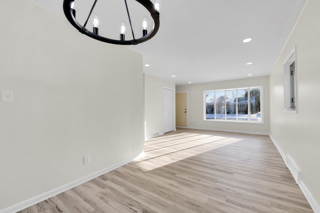 unfurnished living room featuring a chandelier and light hardwood / wood-style flooring