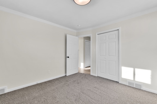 unfurnished bedroom featuring crown molding, carpet flooring, and a closet