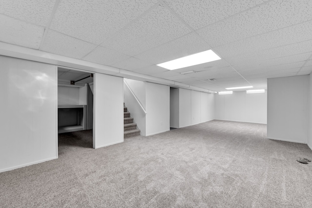 basement featuring a paneled ceiling and carpet