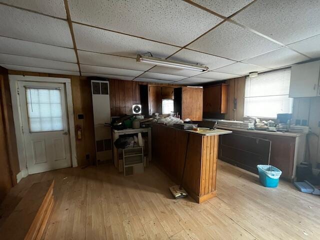 kitchen featuring kitchen peninsula, light hardwood / wood-style flooring, and a drop ceiling