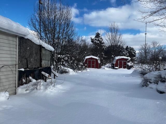 snowy yard featuring a shed