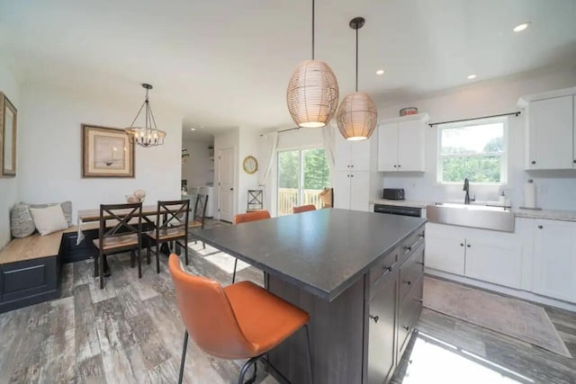 kitchen with a kitchen island, a wealth of natural light, white cabinets, and decorative light fixtures