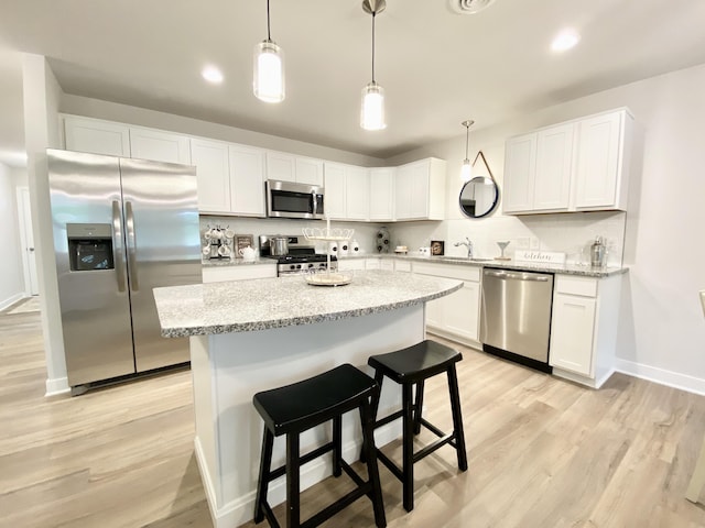 kitchen with white cabinetry, tasteful backsplash, hanging light fixtures, light hardwood / wood-style flooring, and appliances with stainless steel finishes