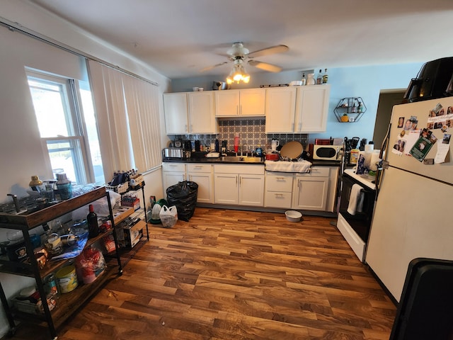 kitchen featuring white fridge, dark hardwood / wood-style floors, white cabinets, and decorative backsplash