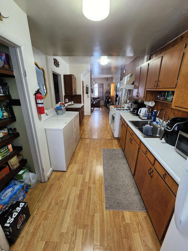 kitchen with white range with gas cooktop, separate washer and dryer, sink, and light wood-type flooring