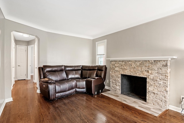 living room with wood-type flooring and a stone fireplace