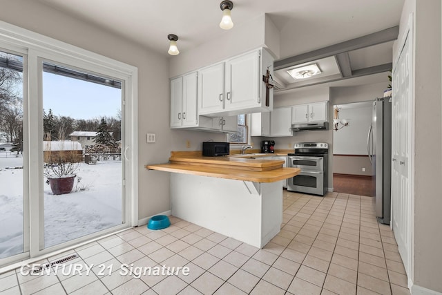 kitchen with a breakfast bar, butcher block countertops, light tile patterned floors, appliances with stainless steel finishes, and white cabinets