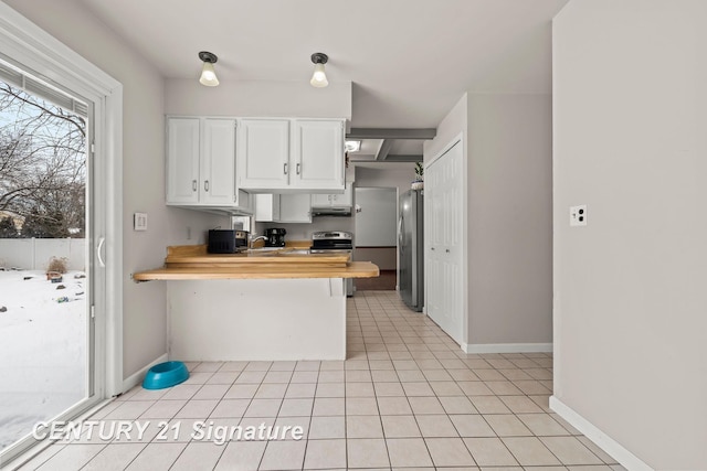 kitchen featuring white cabinetry, wooden counters, light tile patterned floors, a kitchen breakfast bar, and stainless steel appliances