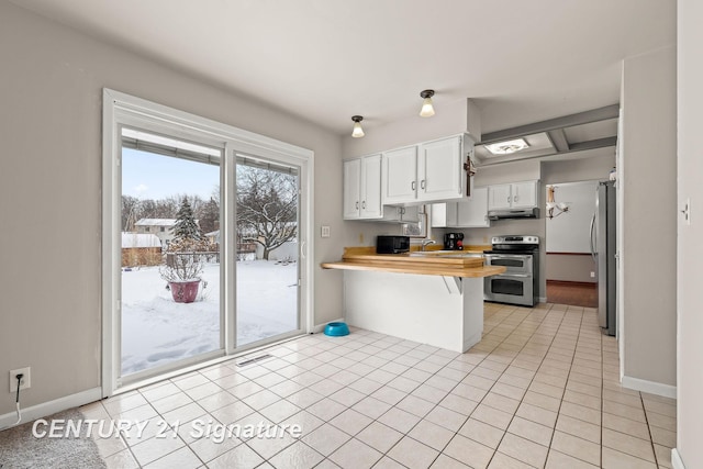 kitchen featuring light tile patterned flooring, a breakfast bar, wood counters, white cabinets, and stainless steel appliances