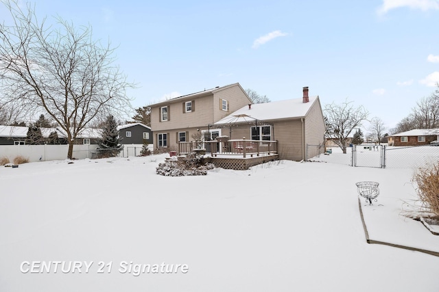 snow covered rear of property with a deck