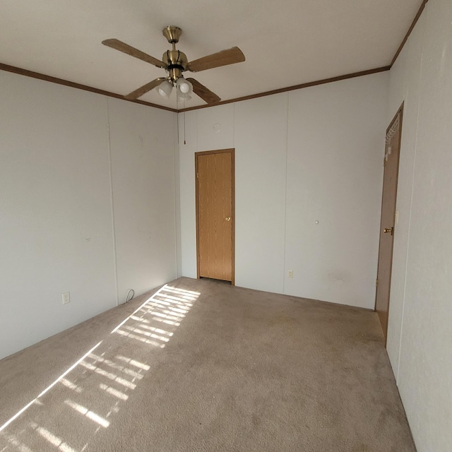 empty room featuring light carpet, crown molding, and ceiling fan