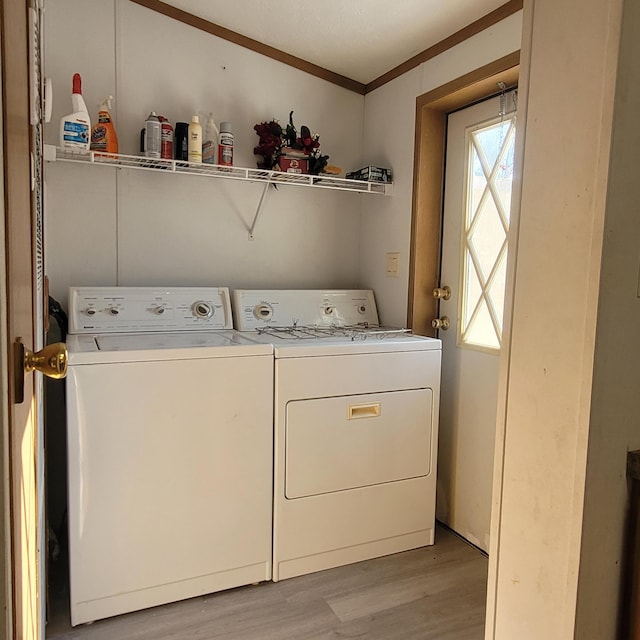 washroom with crown molding, washer and clothes dryer, and light wood-type flooring