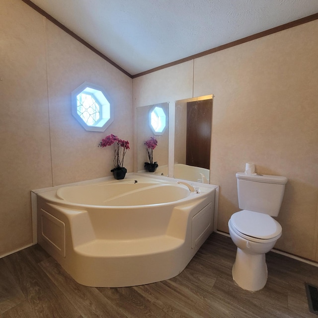 bathroom featuring hardwood / wood-style flooring, toilet, a textured ceiling, and a washtub