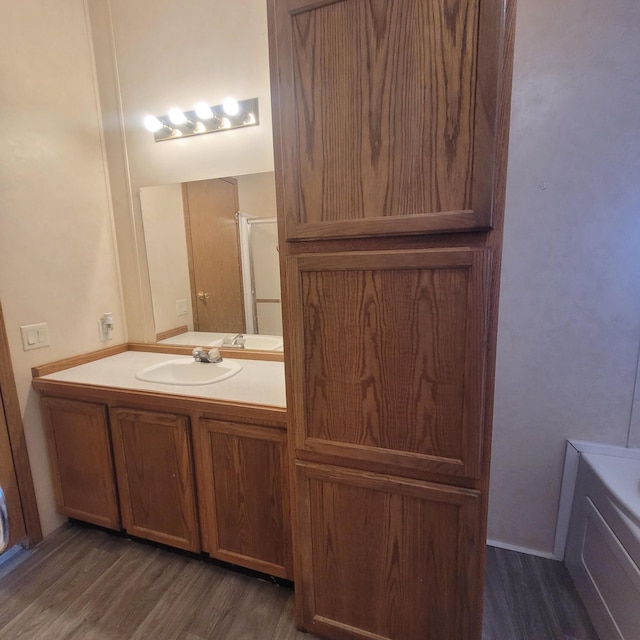 bathroom with hardwood / wood-style flooring, vanity, and a bathtub