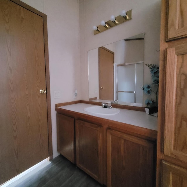 bathroom with an enclosed shower, vanity, and wood-type flooring