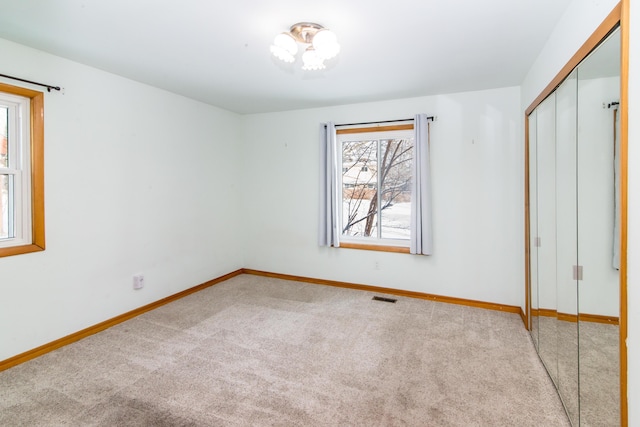 unfurnished bedroom with light carpet and a closet