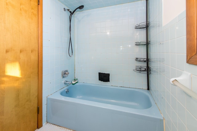 bathroom with tiled shower / bath combo and tile walls