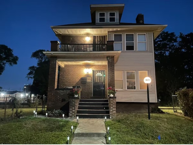 view of front of house featuring a balcony and a yard