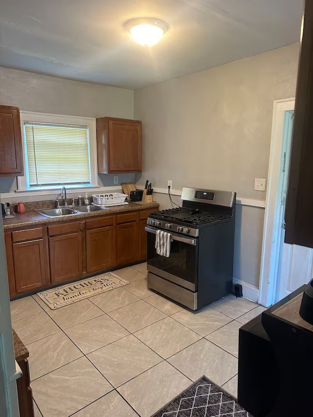 kitchen with sink, gas range, and light tile patterned flooring