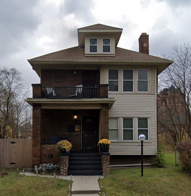 view of front facade with a balcony and a front yard