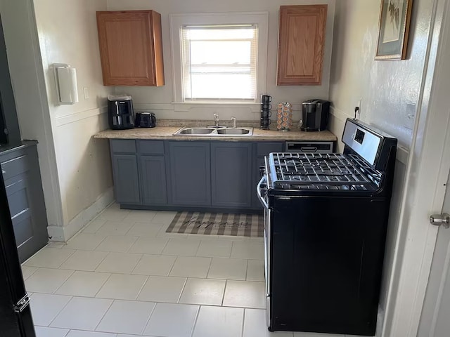 kitchen featuring stainless steel gas stove, sink, light tile patterned floors, and gray cabinetry