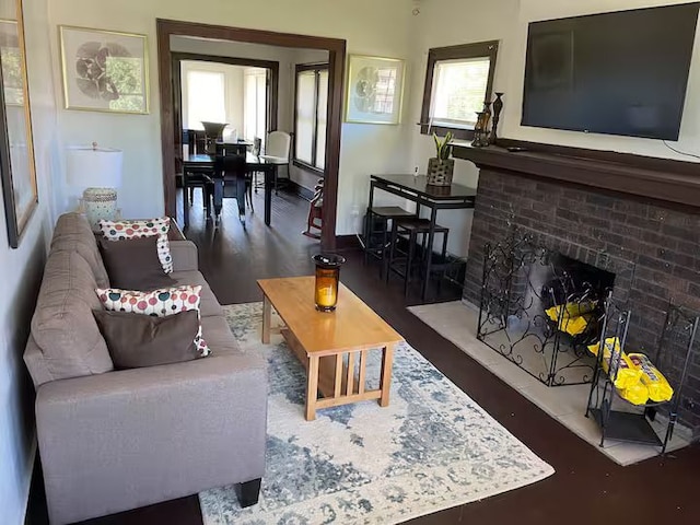 living room featuring dark wood-type flooring, a fireplace, and a wealth of natural light