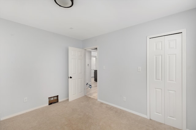 unfurnished bedroom with light carpet and a closet