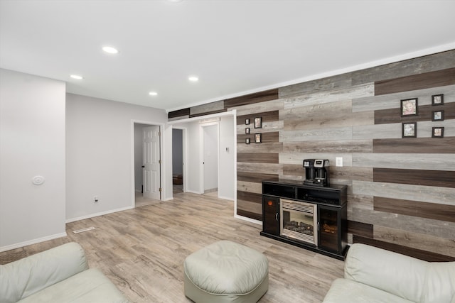 living room featuring light wood-type flooring, a barn door, and wood walls