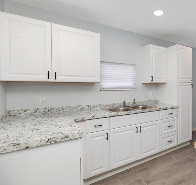 kitchen with light stone countertops, sink, and white cabinets