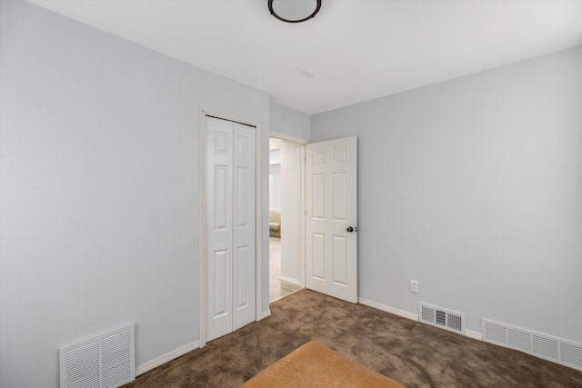 unfurnished bedroom with a closet and dark colored carpet