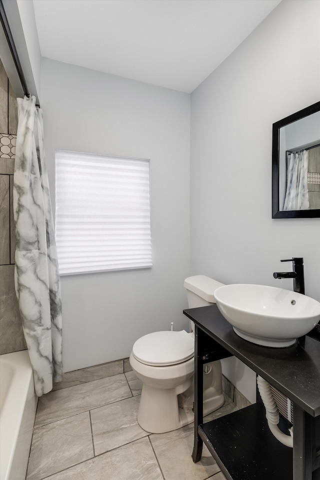 full bathroom featuring sink, shower / bath combo with shower curtain, and toilet