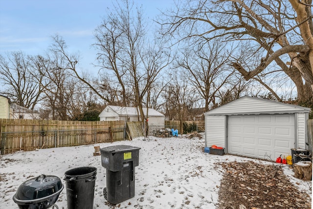 snowy yard with a garage and an outdoor structure